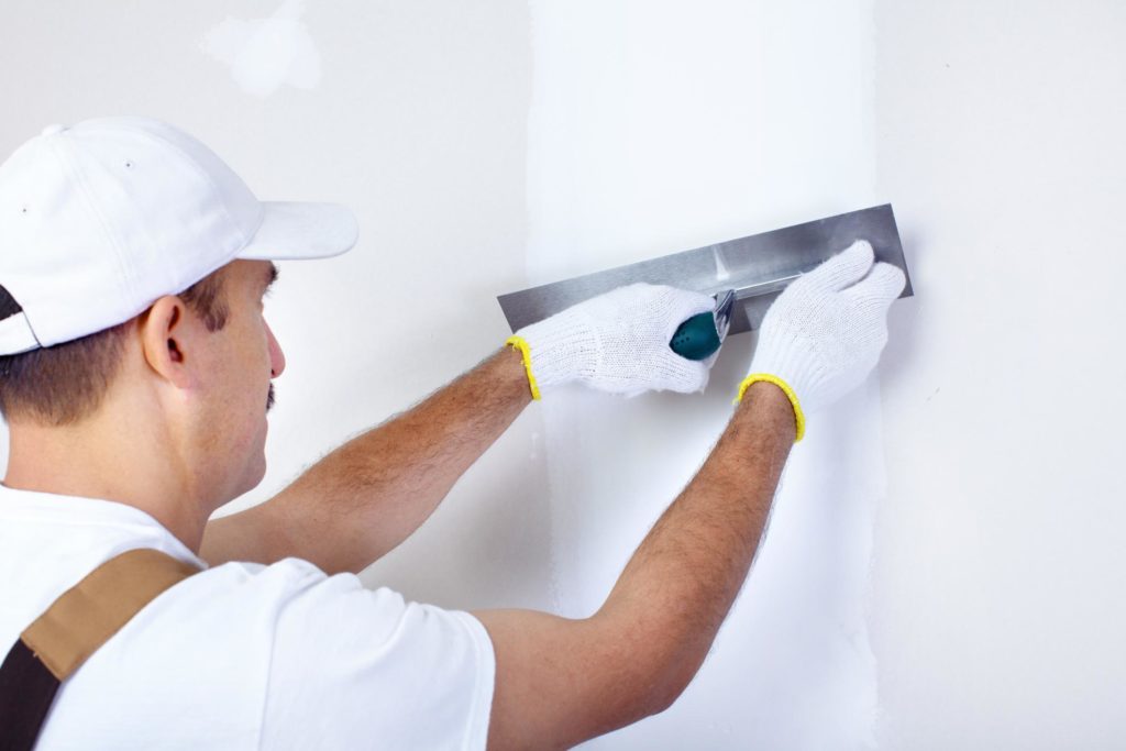 man applying putty on the wall